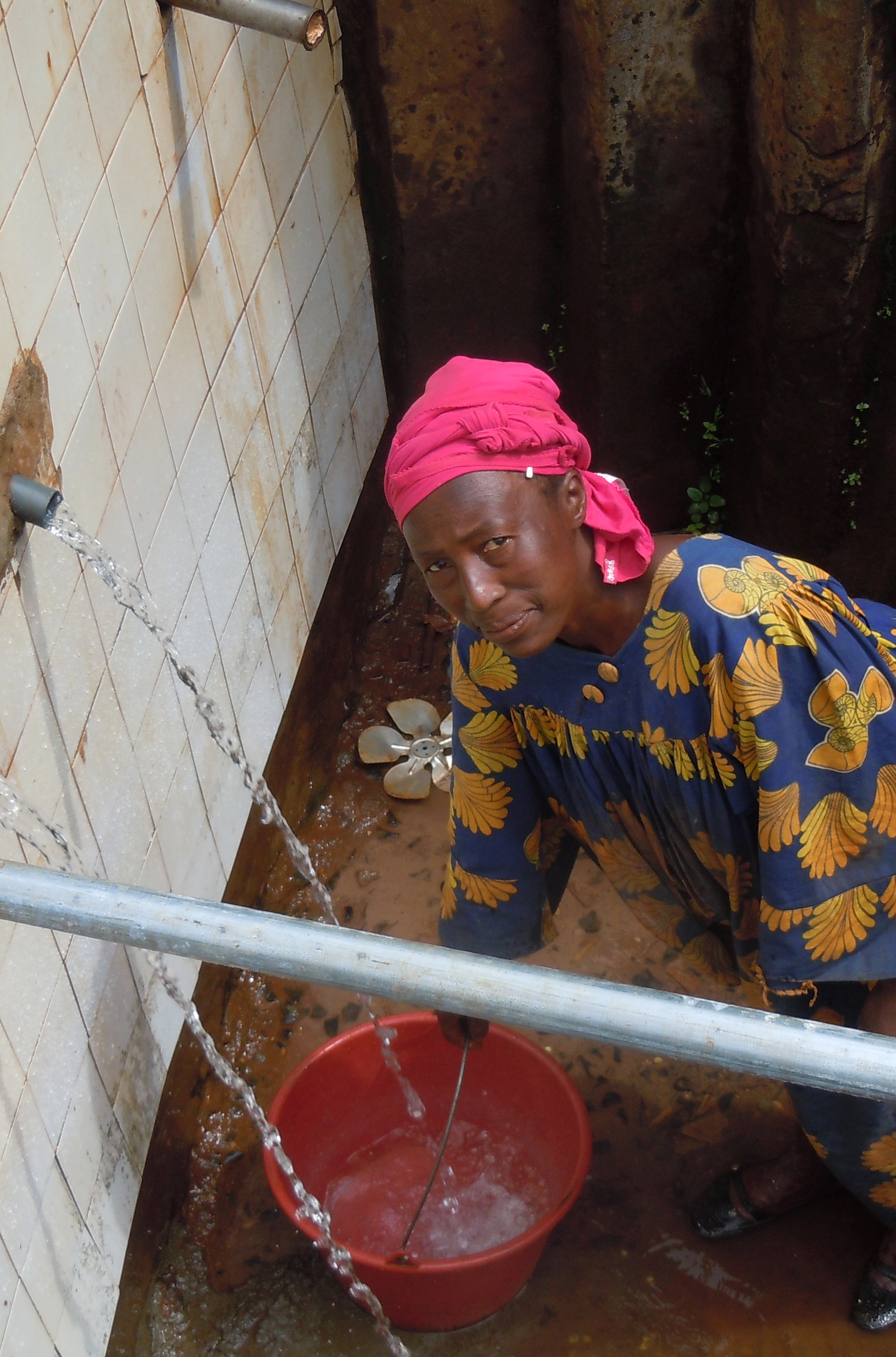 femme en train de remplir une bassine d'eau dans un village camerounais 